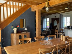 Ein Holztisch mit Stühlen, eine Holzkommode mit Spiegel und eine Treppe.