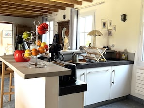 Eine Küche mit weißen Schränken, einer Kaffeemaschine, einer Obstschale und einem Wäscheständer aus Holz.