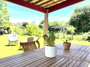 Ein Gartentisch aus Holz mit zwei Blumentöpfen, einem weißen Stuhl und einer Holzbank.