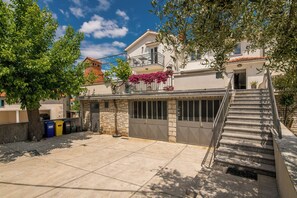 Un edificio residencial con balcón, escaleras y puerta de garaje.