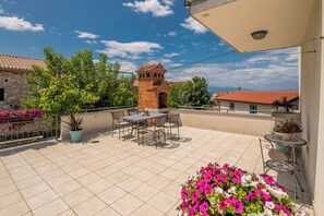 Una terraza en la azotea con una mesa y sillas, una chimenea de ladrillo y plantas en macetas.