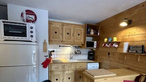 Een kleine keuken met een magnetron, broodrooster en houten keukenkastjes.