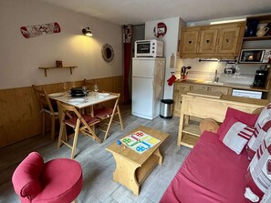 Un espacio habitable compacto con una mesa de comedor, un sofá, una pequeña cocina y una mesa de juegos para niños.