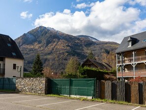 Blick auf Berge mit einer Steinmauer, einem grünen Zaun und einem Gebäude mit Balkon.