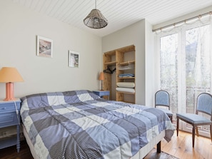 Ein Schlafzimmer mit einem Bett, einem Holzschrank, einem Schreibtisch, einem Stuhl und einer Pendelleuchte.