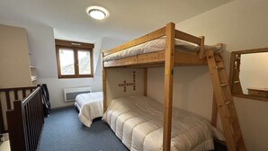 Ein Schlafraum mit Etagenbett, Fenster und Heizkörper.