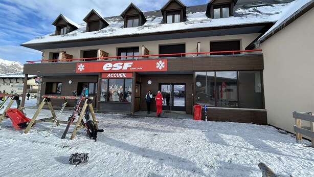 Ein Hotel mit Skilift, Holzfassade und einem Schild mit der Aufschrift 'ESF Saint Lary Accueil'.
