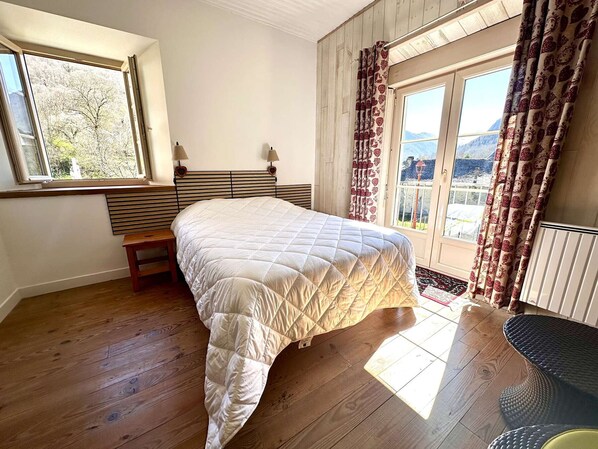 A bedroom with a bed, a bench, a window, and a view of a mountain. - Charming house, 6 guests, Louron Valley (Bordères-Louron)