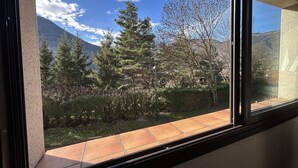 A window with a view of a mountainous landscape, trees, and a clear sky.