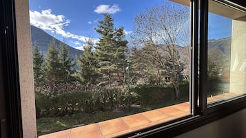 A window with a view of a mountainous landscape, trees, and a clear sky.