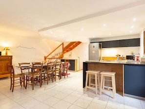 A modern kitchen with a central island, wooden chairs, a dining table, and a staircase. - Spacious house, garden, mountain view - 10 guests (Arreau)
