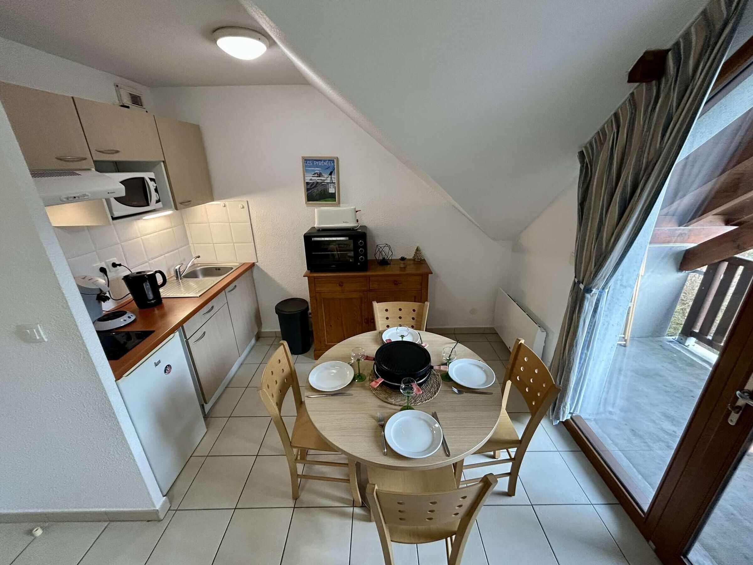 Une cuisine compacte avec un coin repas, un four à micro-ondes, un grille-pain et une petite table mise pour deux personnes.