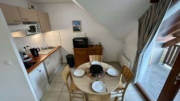 Une cuisine compacte avec un coin repas, un four à micro-ondes, un grille-pain et une petite table mise pour deux personnes.