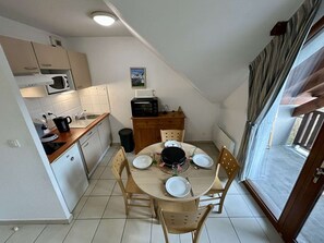 A compact kitchen with a dining area, a microwave, a toaster, and a small table set for two. - Studio cabin with wifi and parking - 4 guests (Arreau)