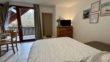 Une chambre à coucher avec un lit, un bureau, une chaise, une commode et un téléviseur.