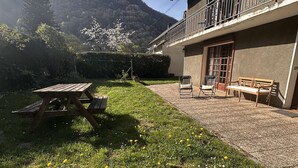 A patio with a wooden table and chairs, a bench, and a view of a mountain. - Single-storey house with garden - 6 guests (Cadéac)
