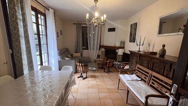 A furnished living room with a dining table, sofa, chairs, a fireplace, and a chandelier. - Single-storey house with garden - 6 guests (Cadéac)