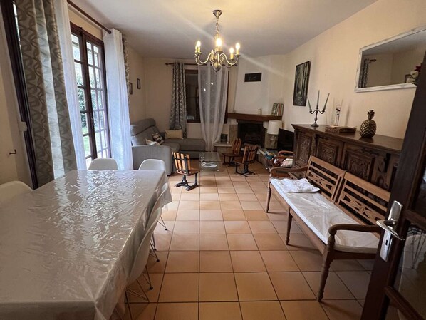 Una sala de estar amoblada con una mesa de comedor, sofá, sillas, chimenea y candelabro.
