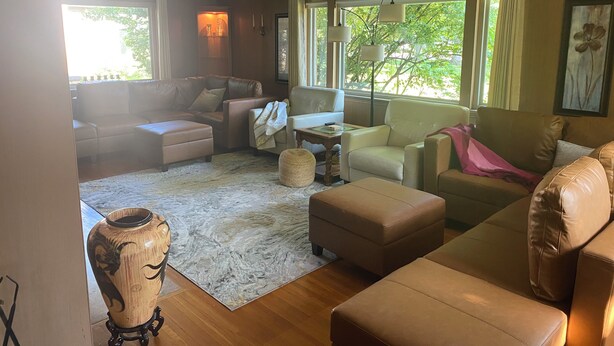 Uma sala de estar com sofá, poltronas, mesa de centro e um vaso decorativo.