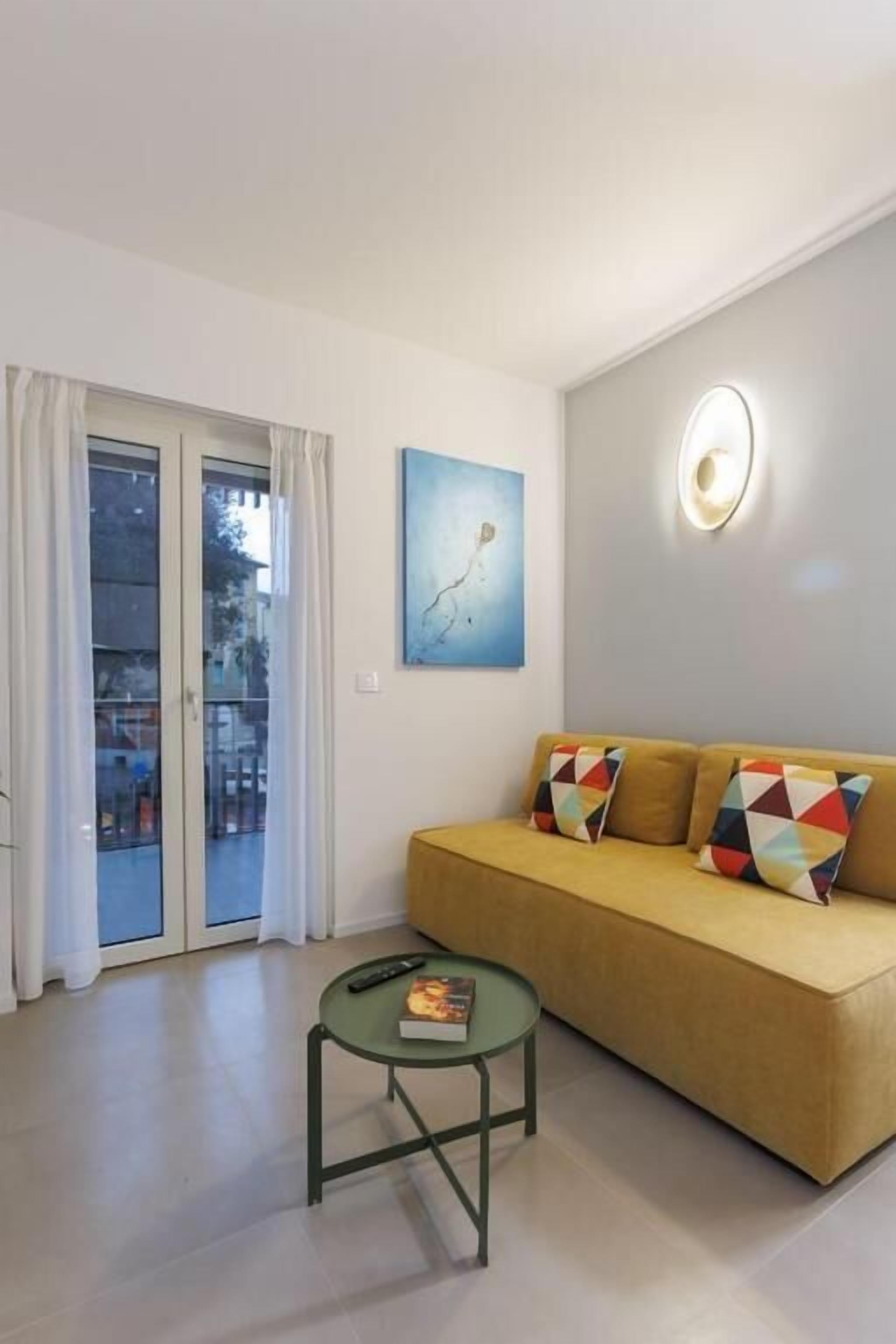 A living room with a sofa, a coffee table, a painting, and a door with glass panels.