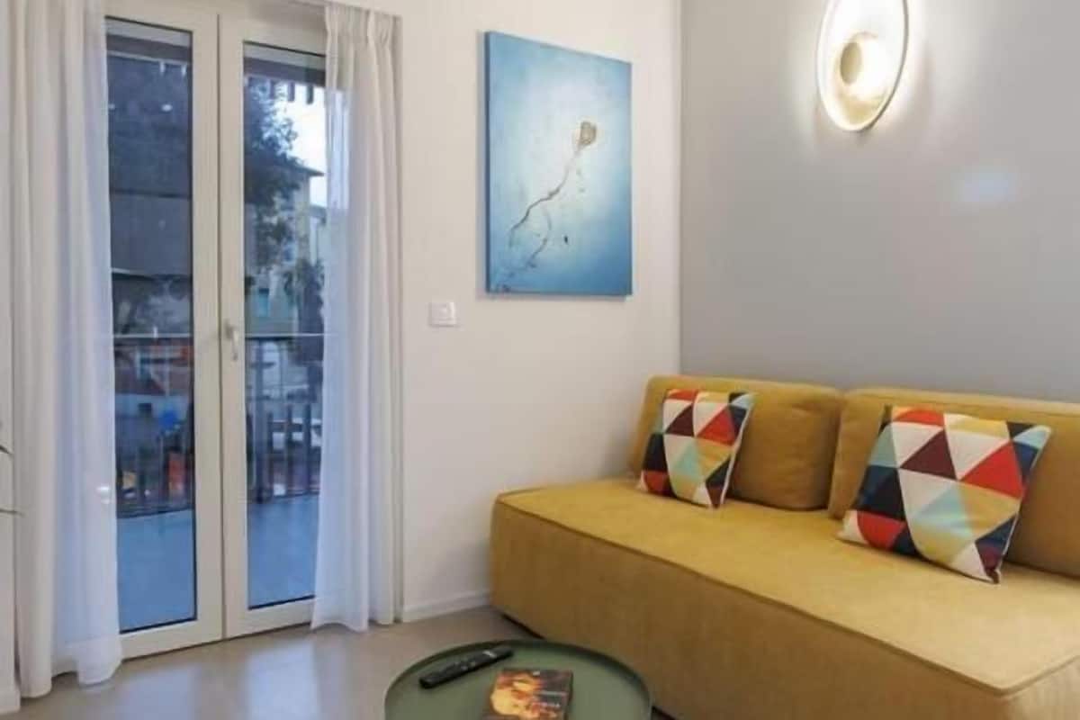 A living room with a sofa, a coffee table, a painting, and a door with glass panels.