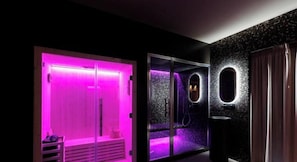 A spa room with a purple-lit shower, a glass door, and a textured wall. - ZENIT APPARTAMENTI & SPA (Terni)