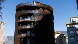 Un edificio de varios pisos con balcones, un diseño en espiral y un cielo despejado al fondo.