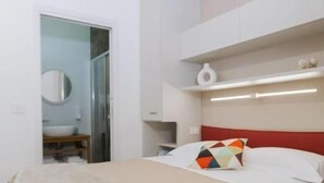 Un dormitorio con una cama, una mesita de noche, un espejo y un armario.