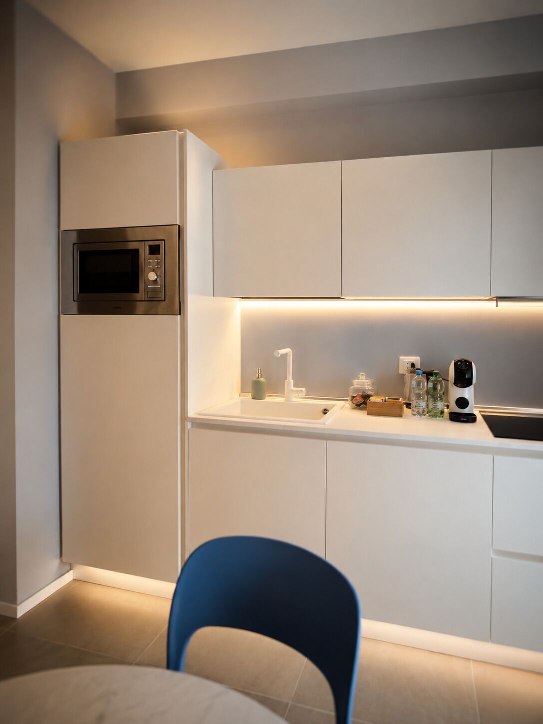 A modern kitchen with a built-in microwave, a sink, and a coffee maker on the countertop.