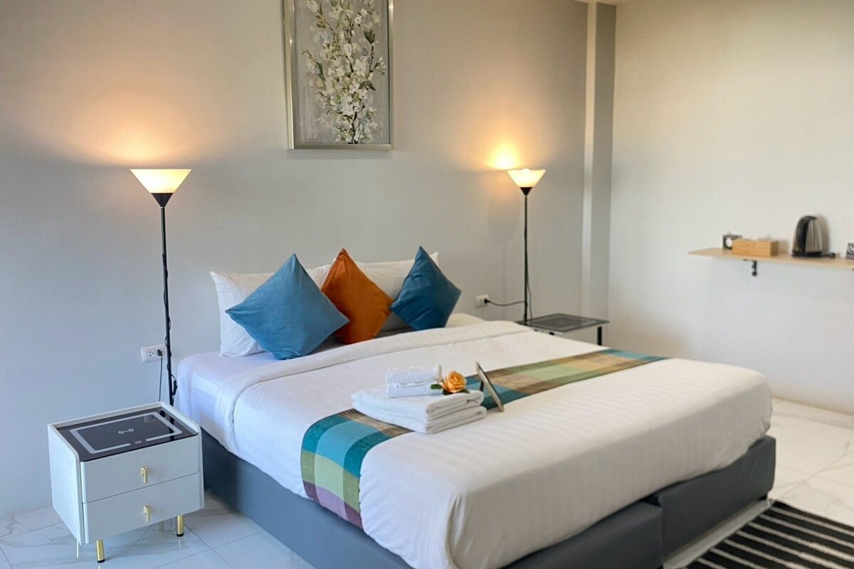 Una habitación de hotel moderna con una cama, mesitas de noche, una lámpara y un cuadro en la pared.