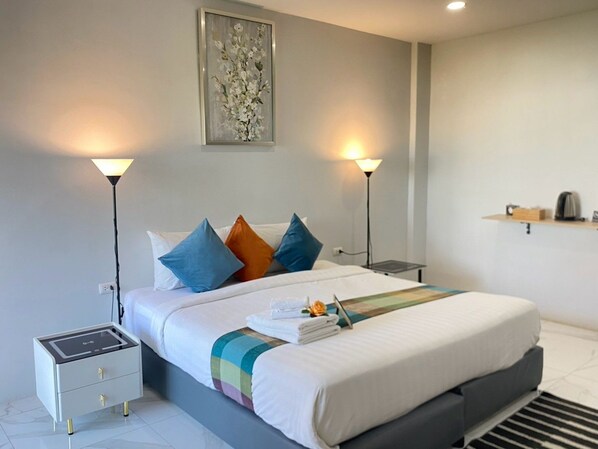 A modern hotel room with a bed, bedside tables, a lamp, and a painting on the wall.