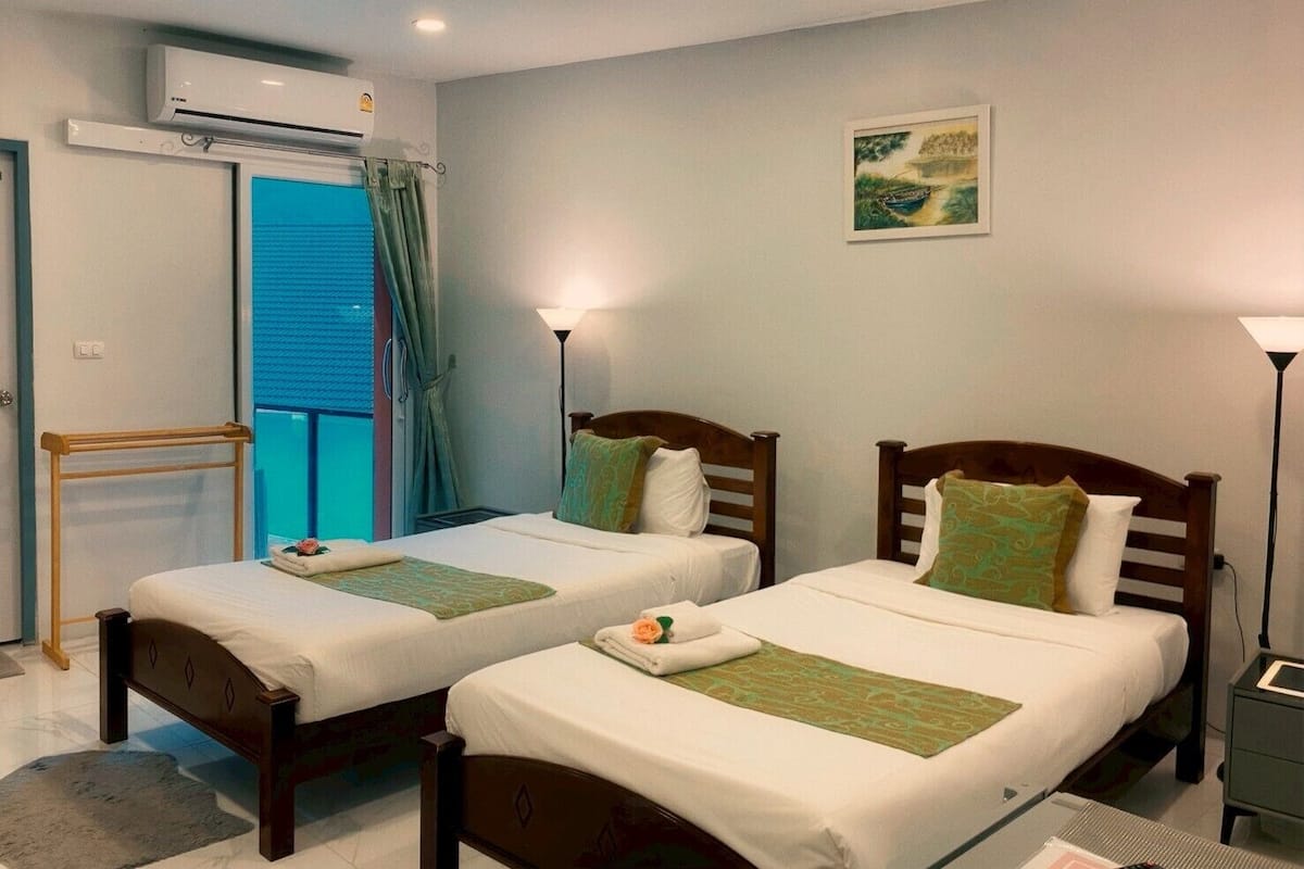 A hotel room with two beds, a balcony, an air conditioning unit, and a painting on the wall.