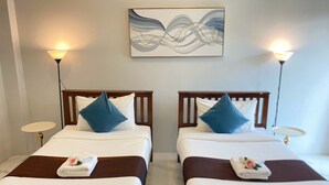 Habitación de hotel con dos camas, cada una con almohada, mesita de noche y lámpara de pared.