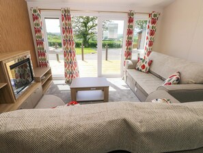 A cozy living room with a sofa, a coffee table, and a fireplace. - Sandpiper (Narberth)