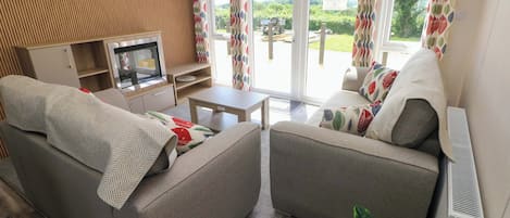 A living room with two sofas, a TV, a small table, and a large window with curtains.