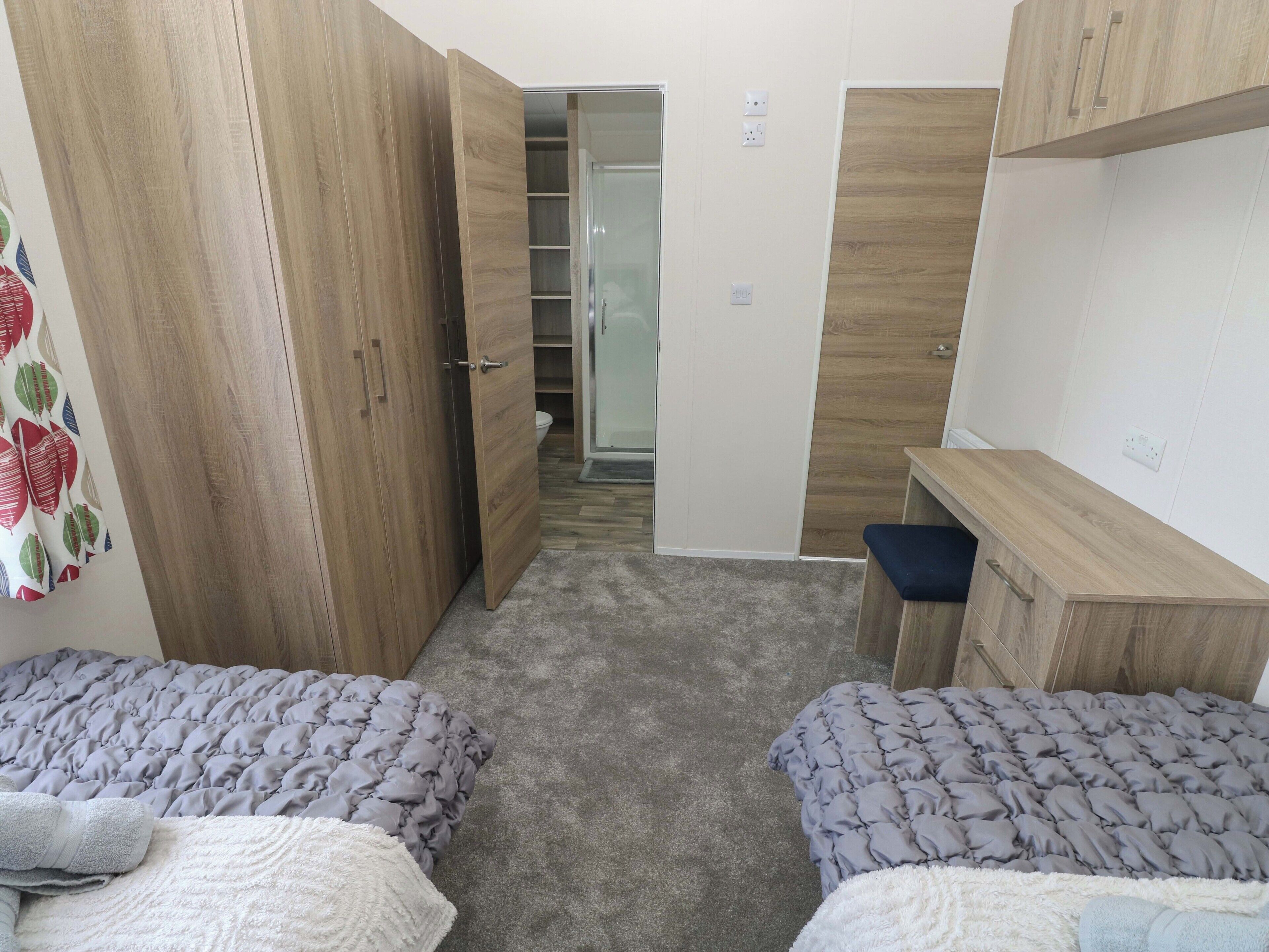 Un dormitorio con dos camas, un armario, un escritorio y un baño.