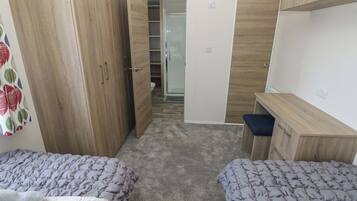 Un dormitorio con dos camas, un armario, un escritorio y un baño.