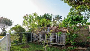 A fenced garden area with a small structure, possibly a shed, surrounded by greenery and trees.