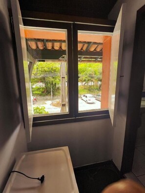 A bathroom with a window, a sink, and a shower area.