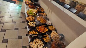 Un buffet con diverse pietanze, tra cui frutta secca, frutta fresca e dolci, disposti su un bancone.