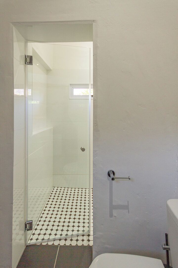 A bathroom with a toilet, a shower with a glass door, and a patterned floor.