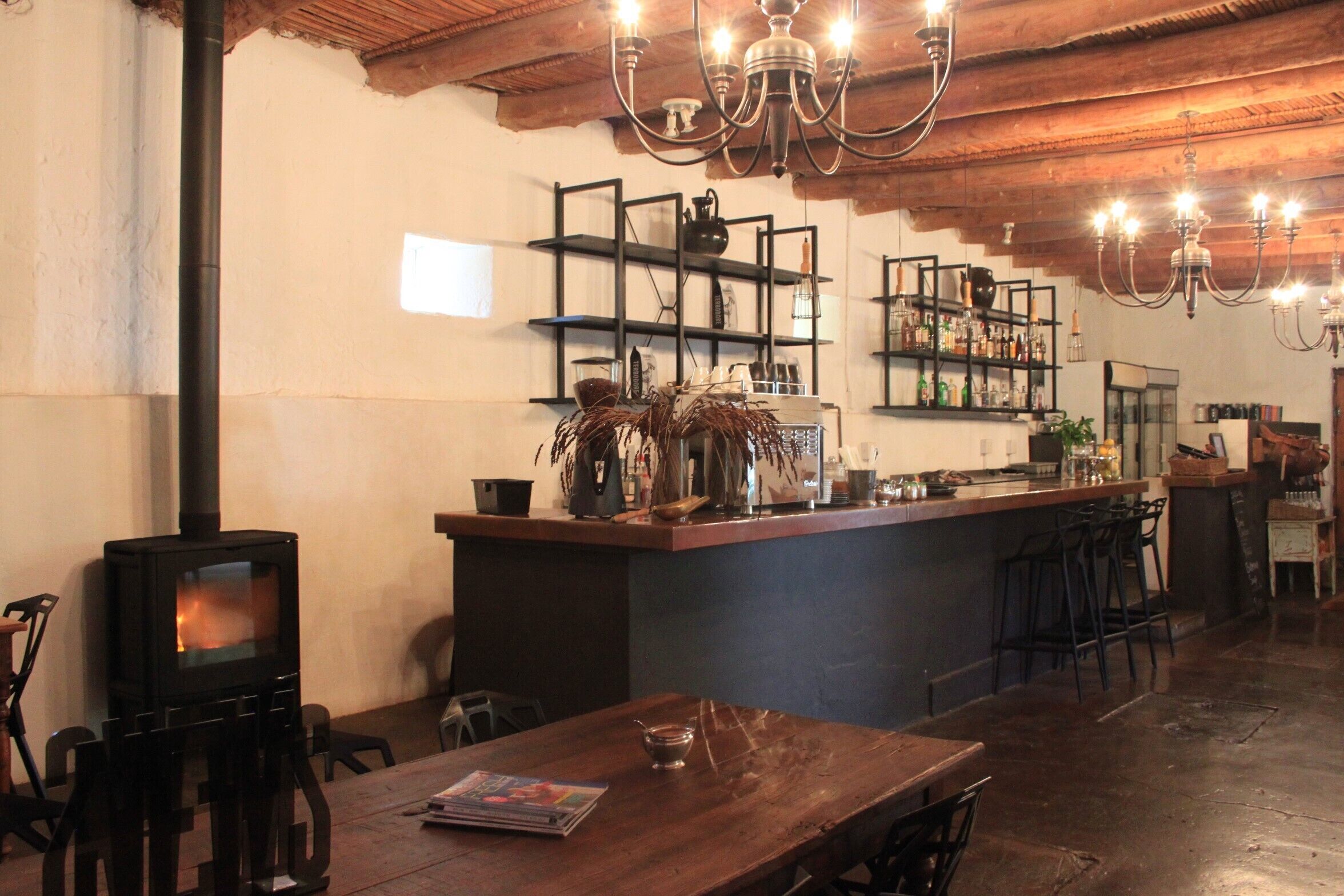 A rustic interior with a wood-burning stove, bar area, and bar stools.