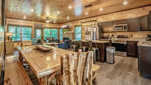 A spacious kitchen with wooden cabinetry, a large island, and a stone fireplace. - SmokySplashRetreat: Pool, Wifi, Hot Tub, Game Room, Partial Mtn Views (Sevierville)