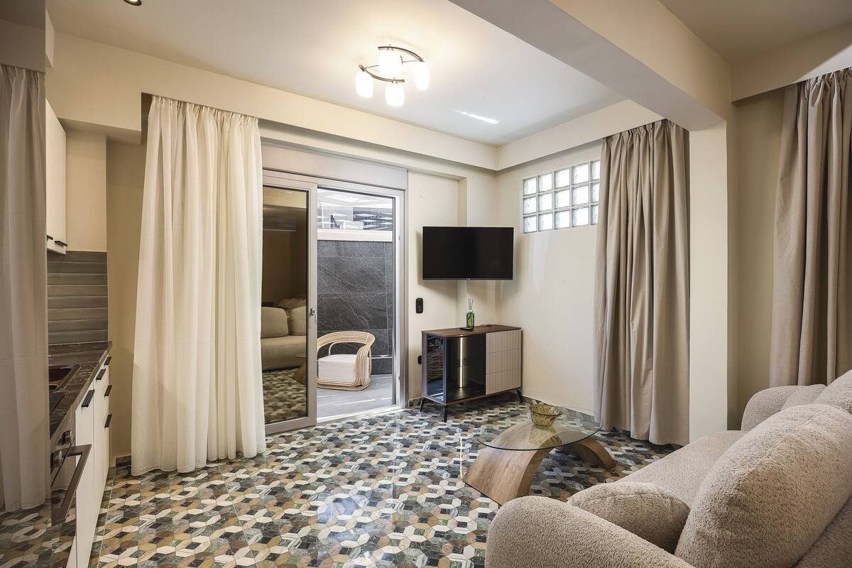 A living room with a sofa, a TV, a cabinet, and a patterned floor.