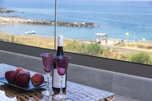 A table with a bottle of wine, two purple wine glasses, and three red apples. - MGM Suites (Panormos in Rethymno)