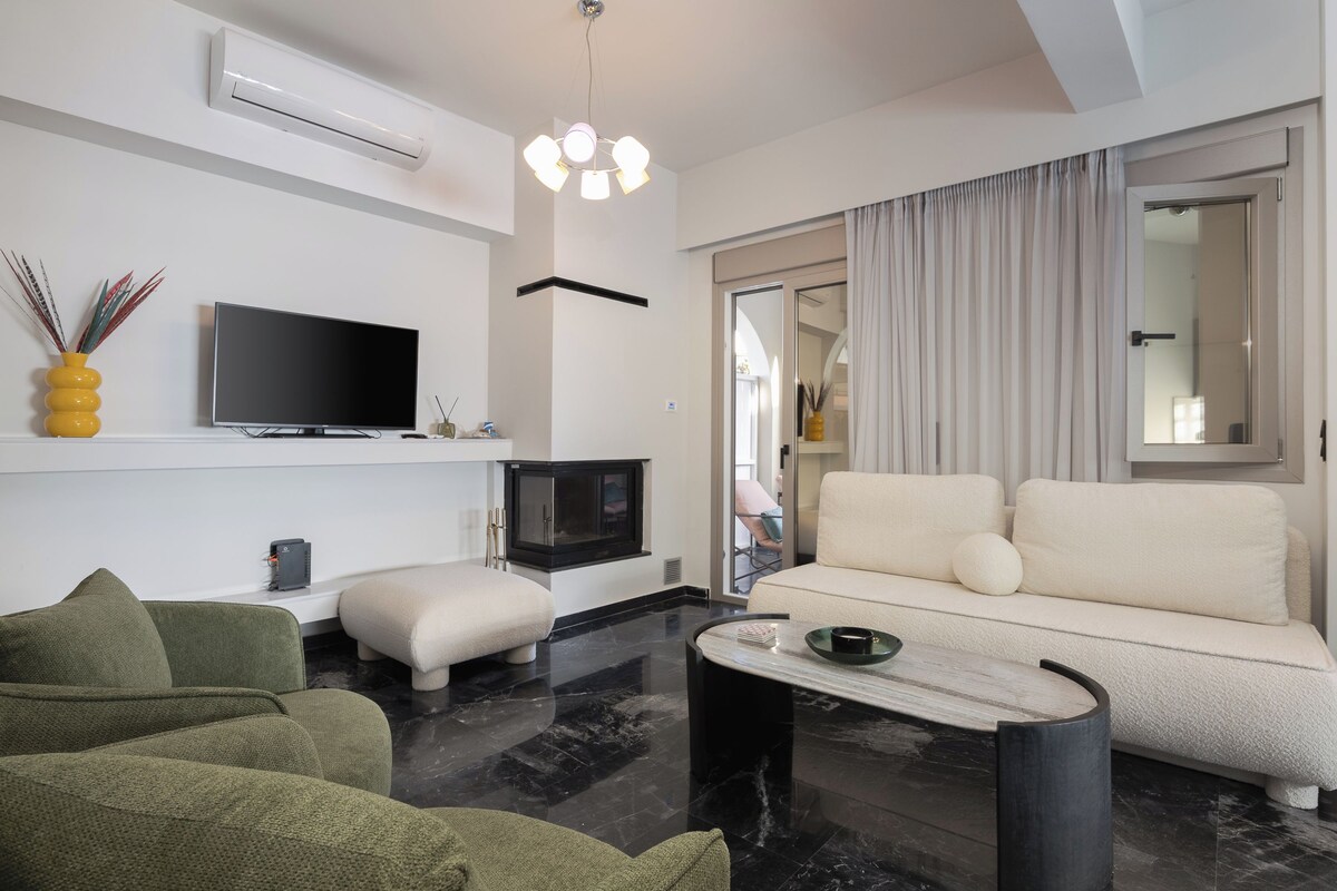 A modern living room with a flat-screen TV, a sofa, a coffee table, and a fireplace.