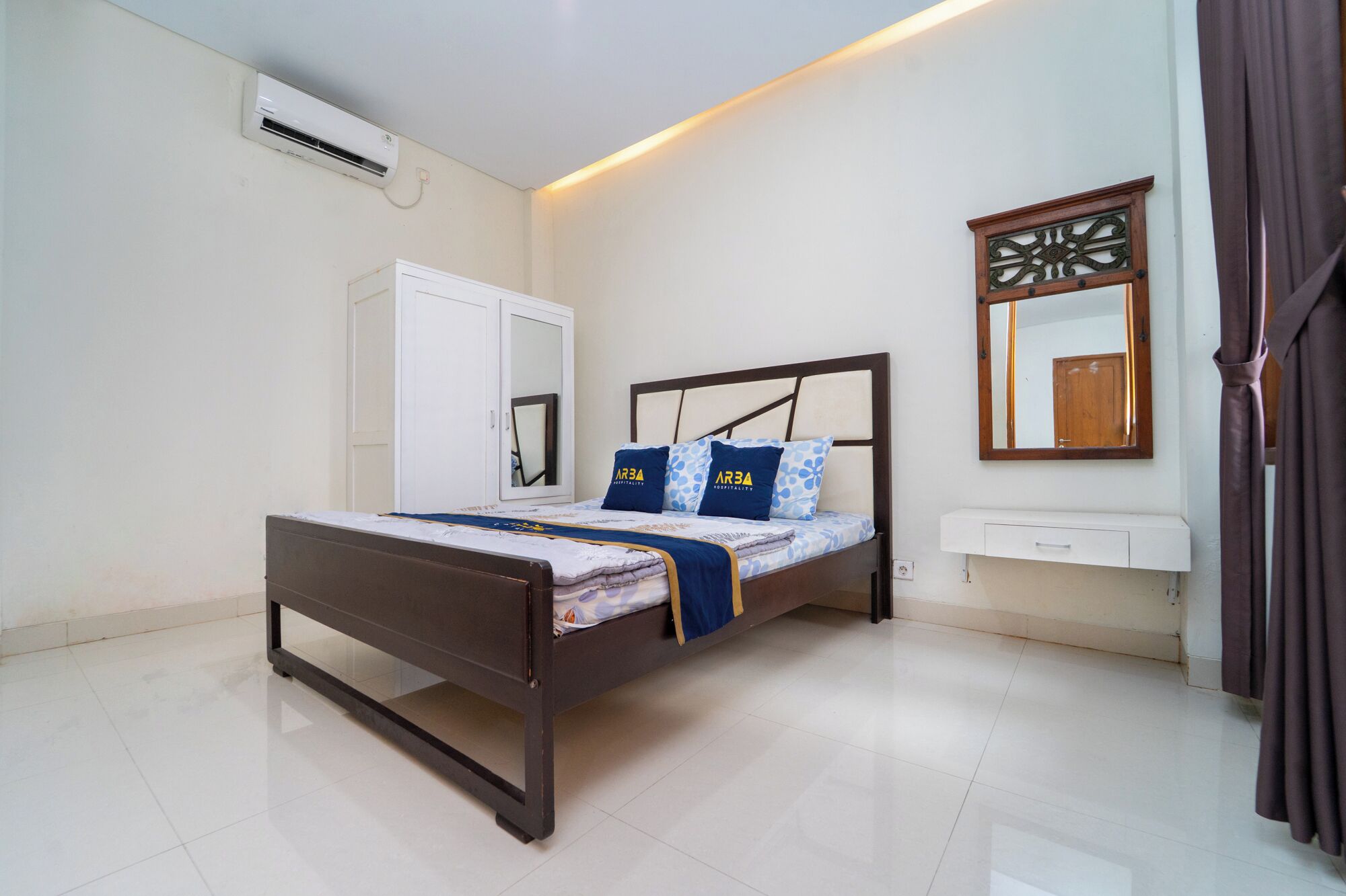A bedroom with a bed, a wardrobe, a mirror, and an air conditioning unit.