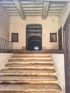 A staircase leading to an arched doorway, with a metal railing on the left and a door on the right.