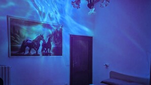 A bedroom with a bed, a door, and a wall-mounted painting of horses.
