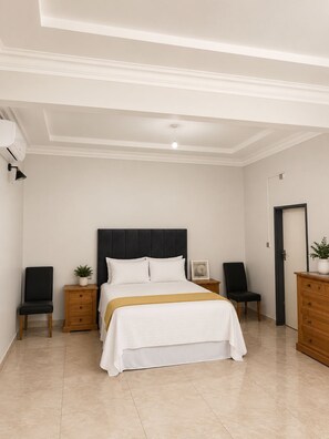 Een slaapkamer met een bed, nachtkastjes, een dressoir, een deur en een plafondlamp.